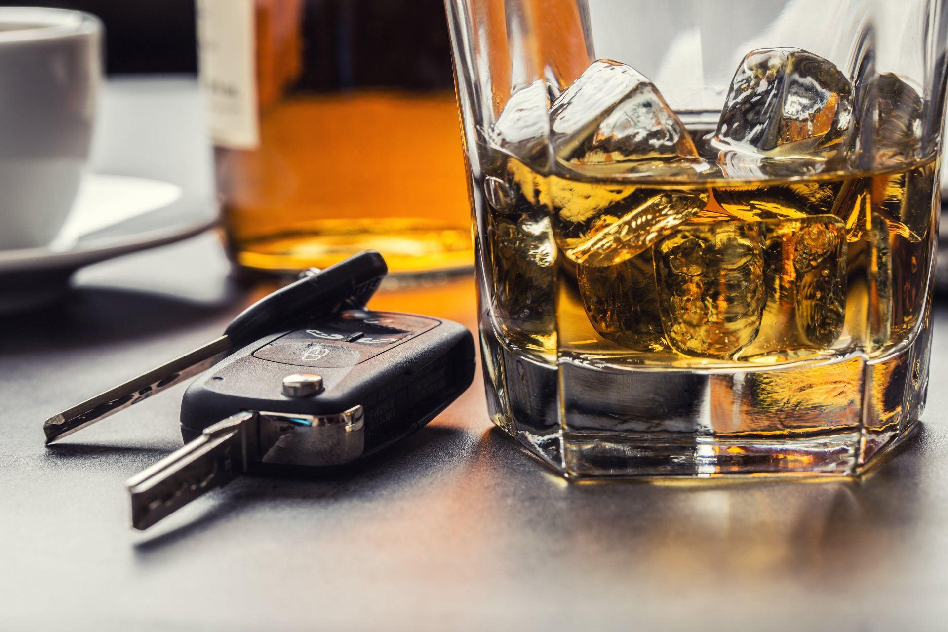 Car keys and glass of alcohol on table.