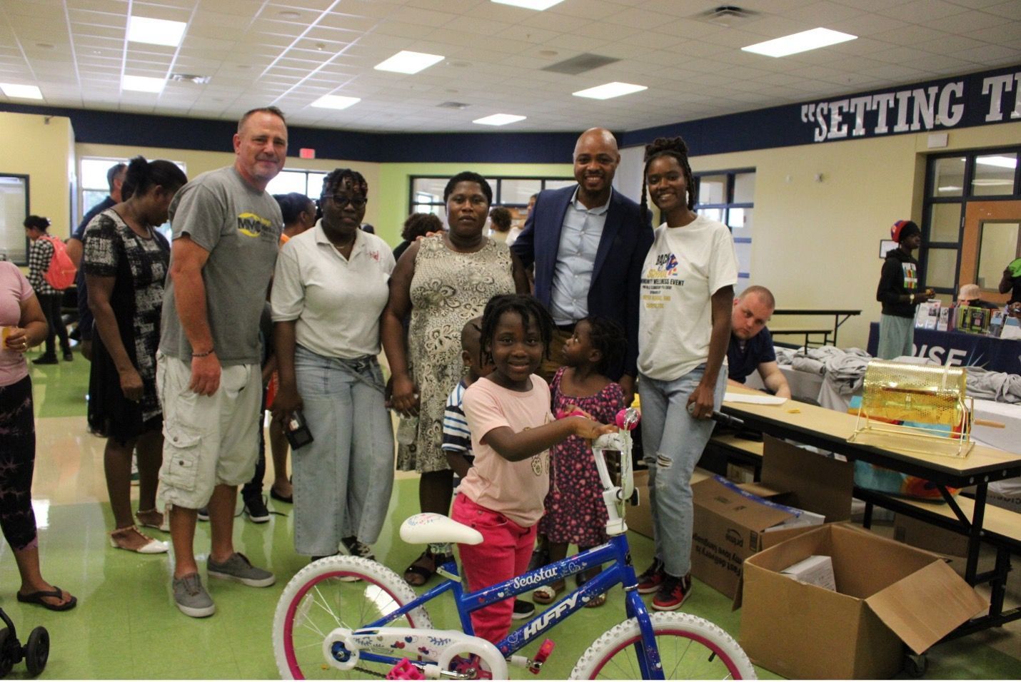 Group smiles with children and a blue bike, in a school setting.