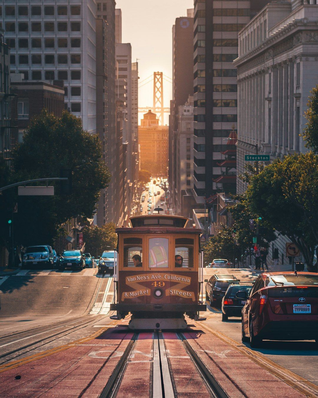 A cable car is going down a city street at sunset.