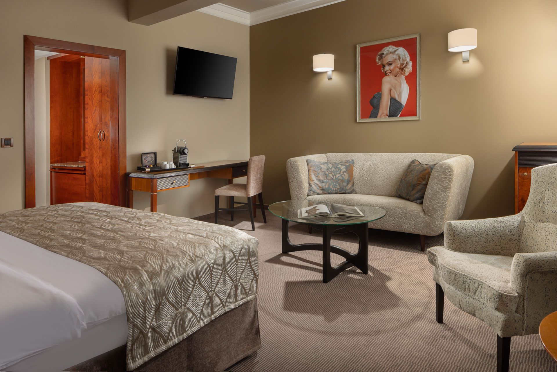 Hotelový pokoj s postelí , gaučem , židlí , stolem a televizí.