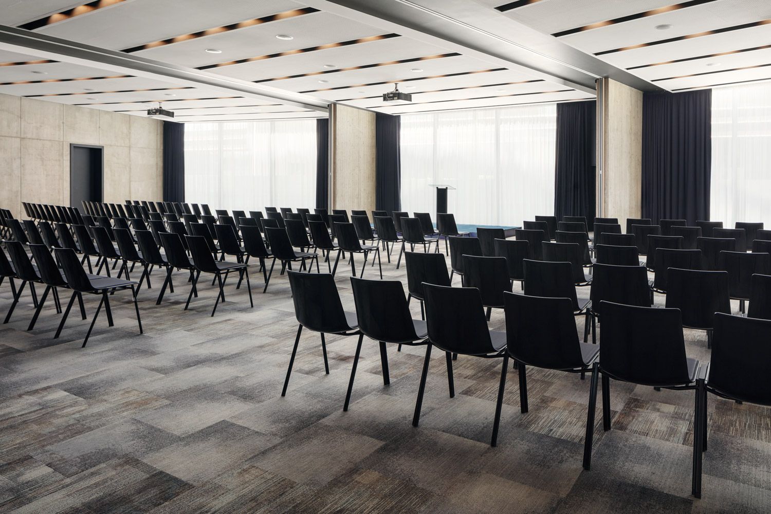 Velká konferenční místnost s řadami černých židlí