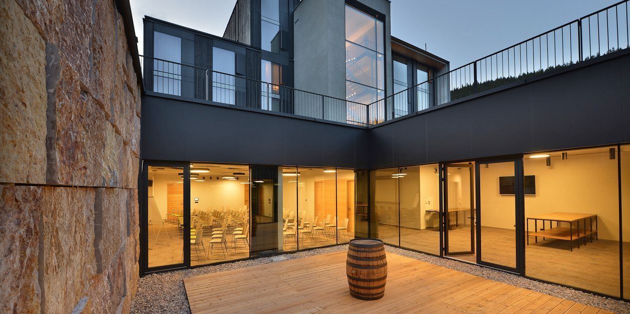 Sud sedí na dřevěné palubě před budovou se spoustou oken.