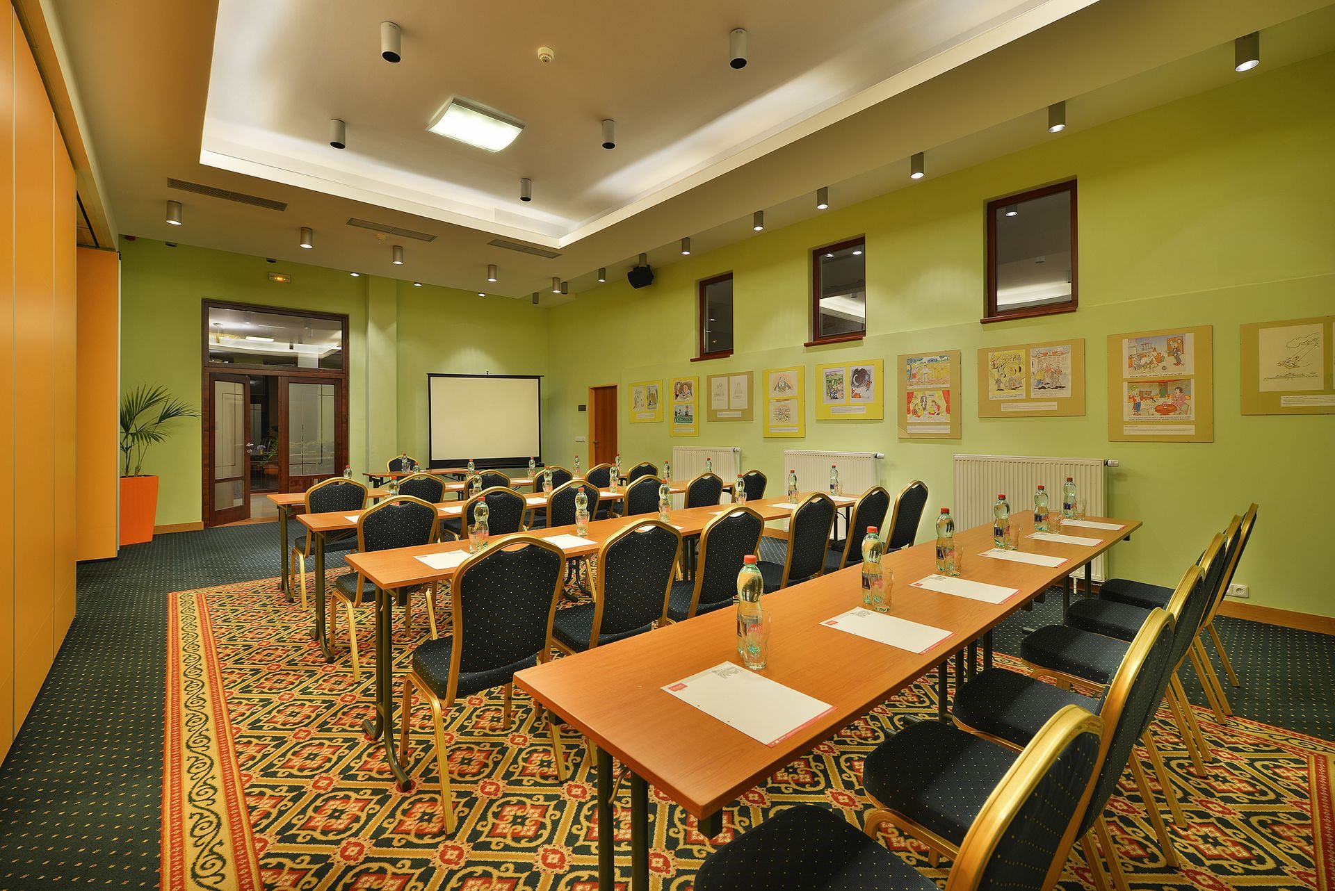 Konferenční místnost se stoly a židlemi a promítacím plátnem