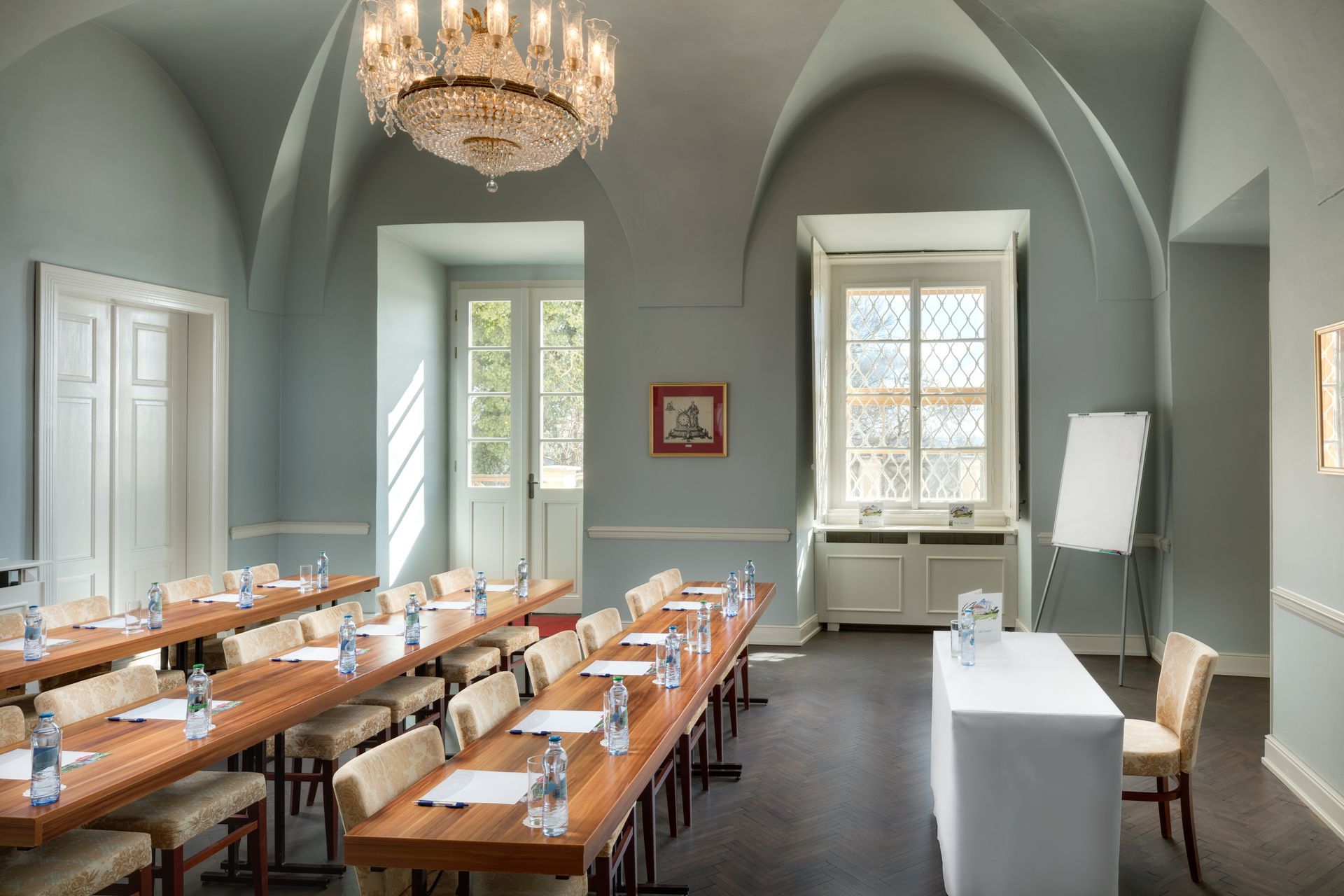 Konferenční místnost se stoly a židlemi a lustrem.