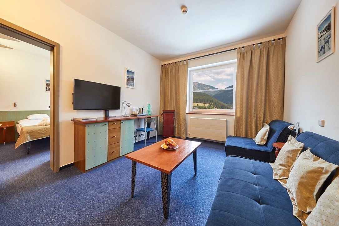 Obývací pokoj s pohovkou, stolem a televizí.