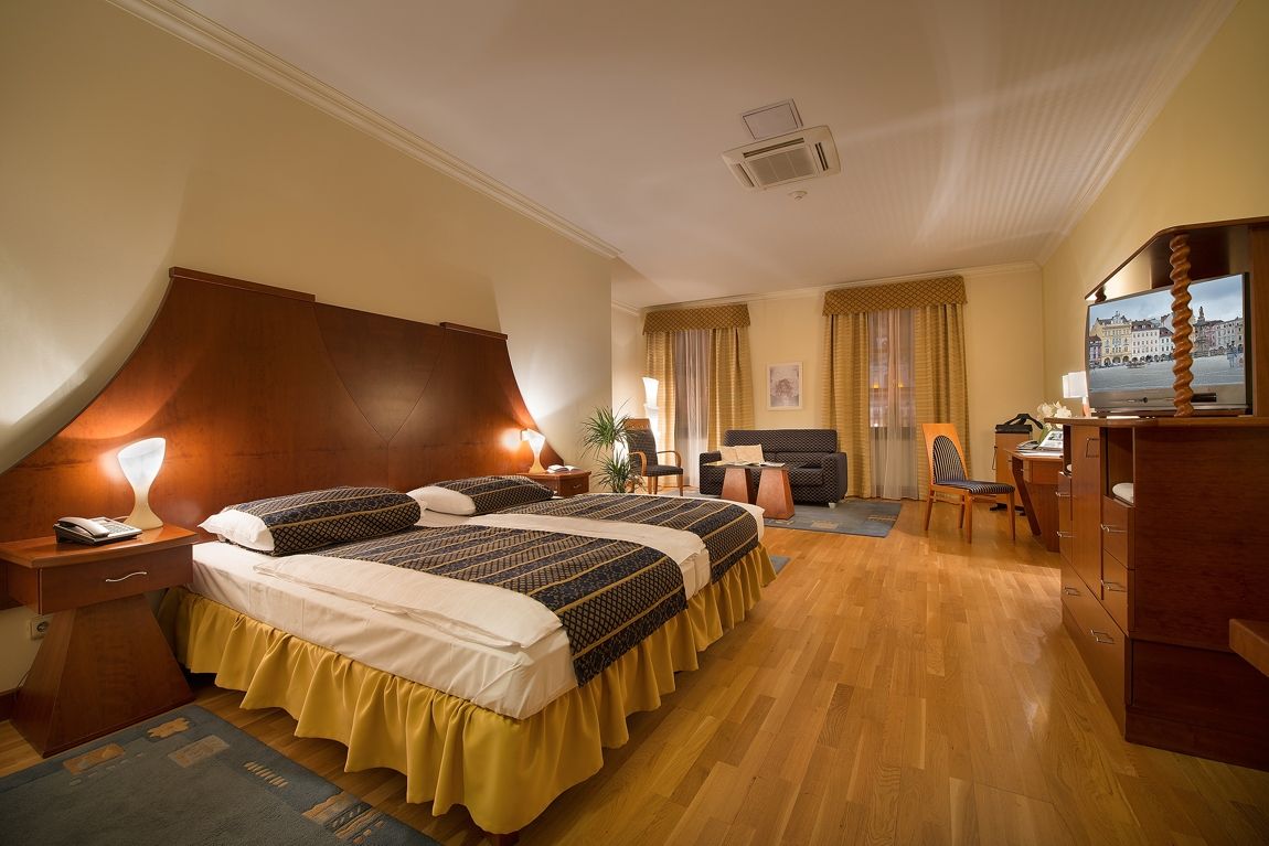 Hotelový pokoj se dvěma lůžky , stolem , židlí a televizí.