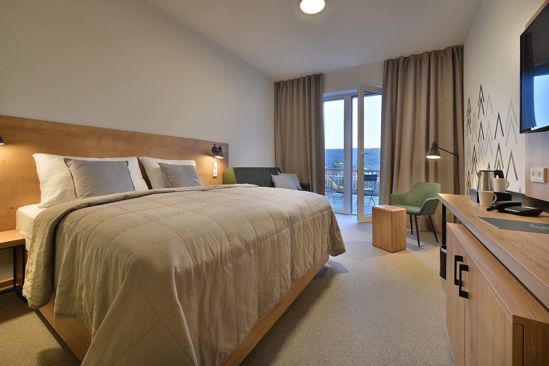 Hotelový pokoj s manželskou postelí , stolem , židlí a televizí.