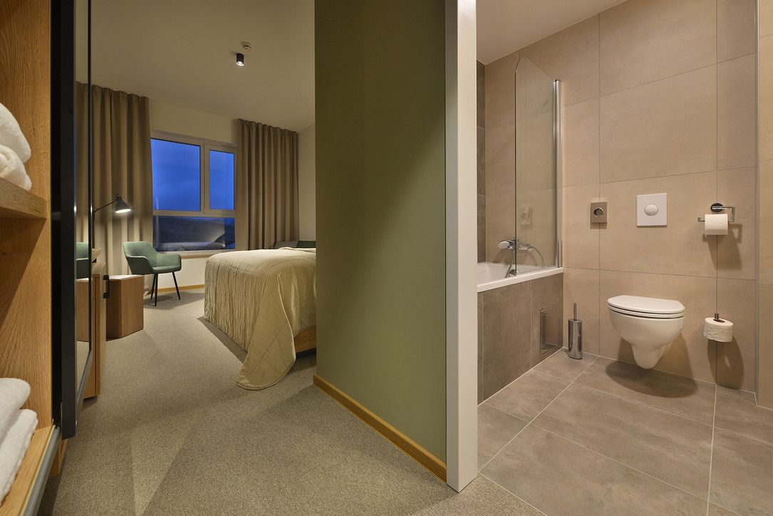 Hotelový pokoj s postelí, toaletou a vanou.