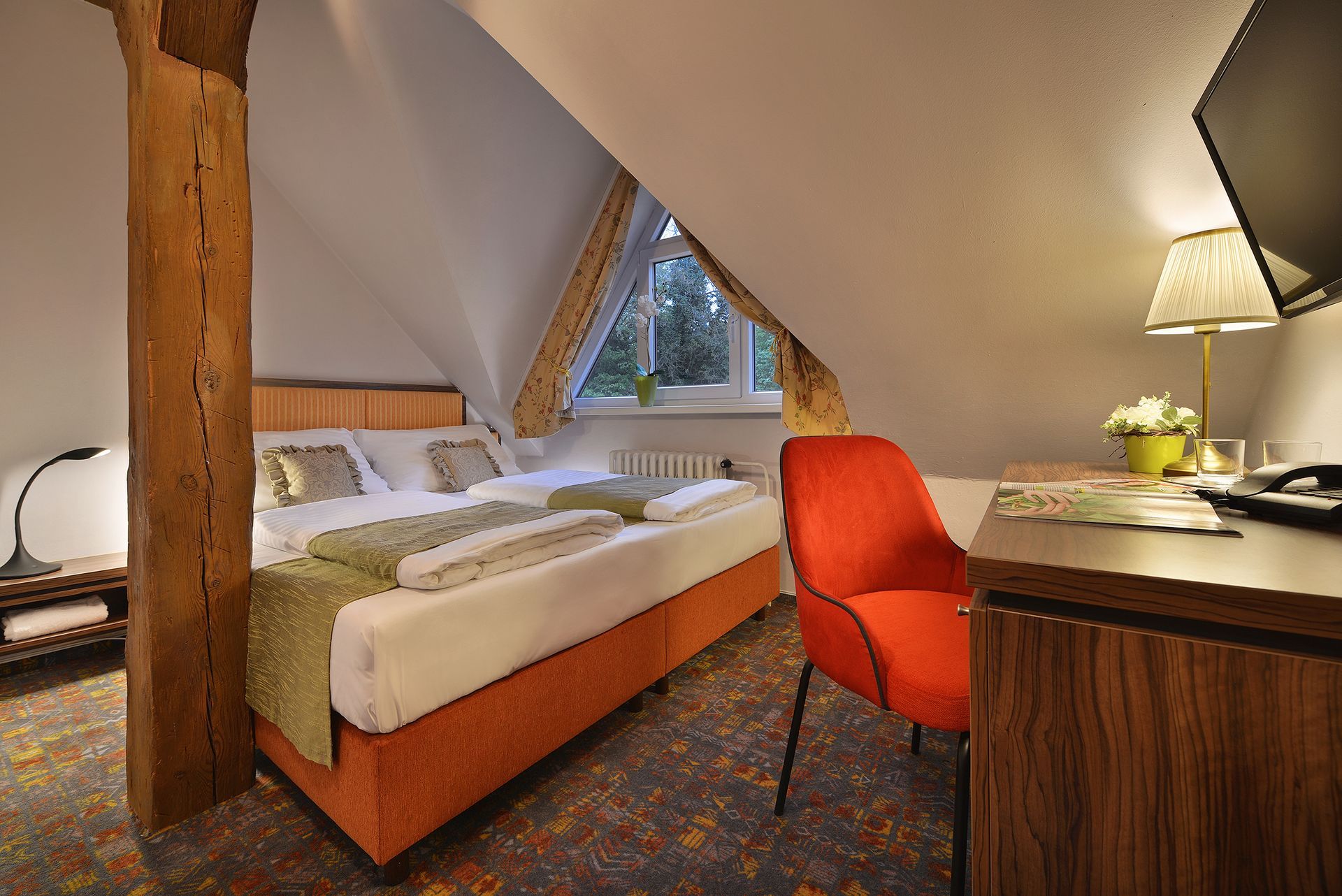 Hotelový pokoj se dvěma lůžky , stolem , židlí a televizí.