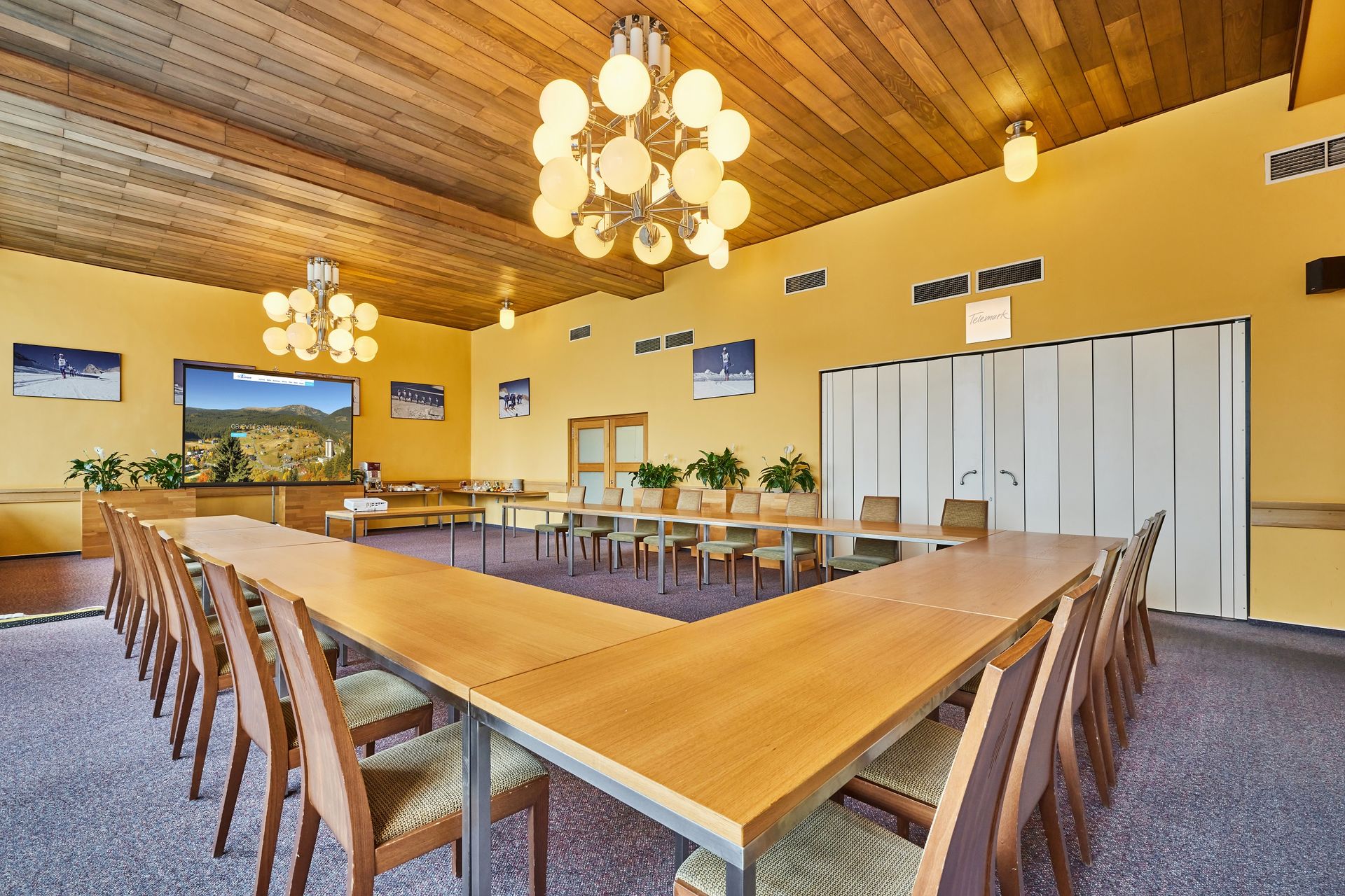 Konferenční místnost se stoly a židlemi a lustrem