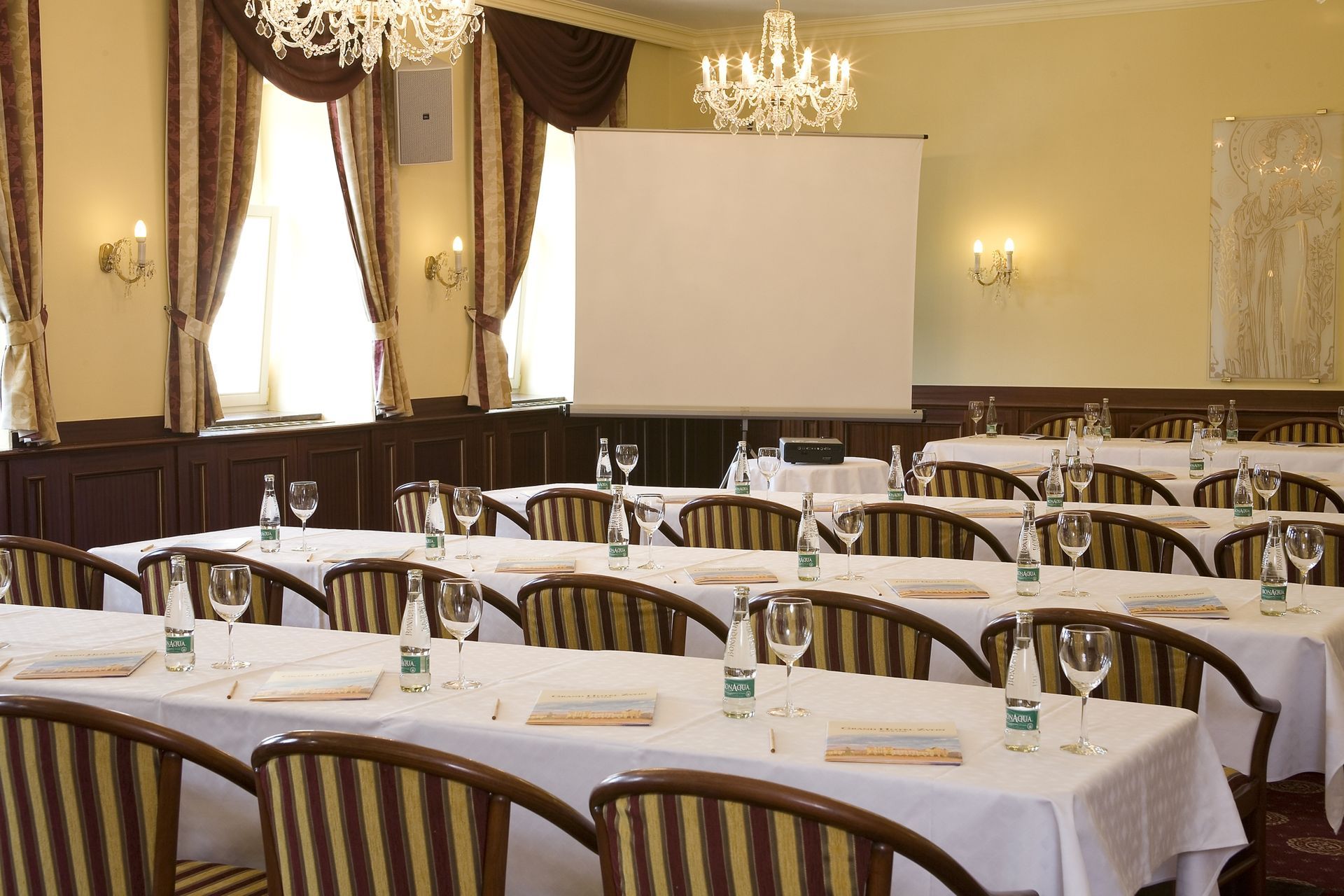 Velká místnost se stoly a židlemi a promítacím plátnem