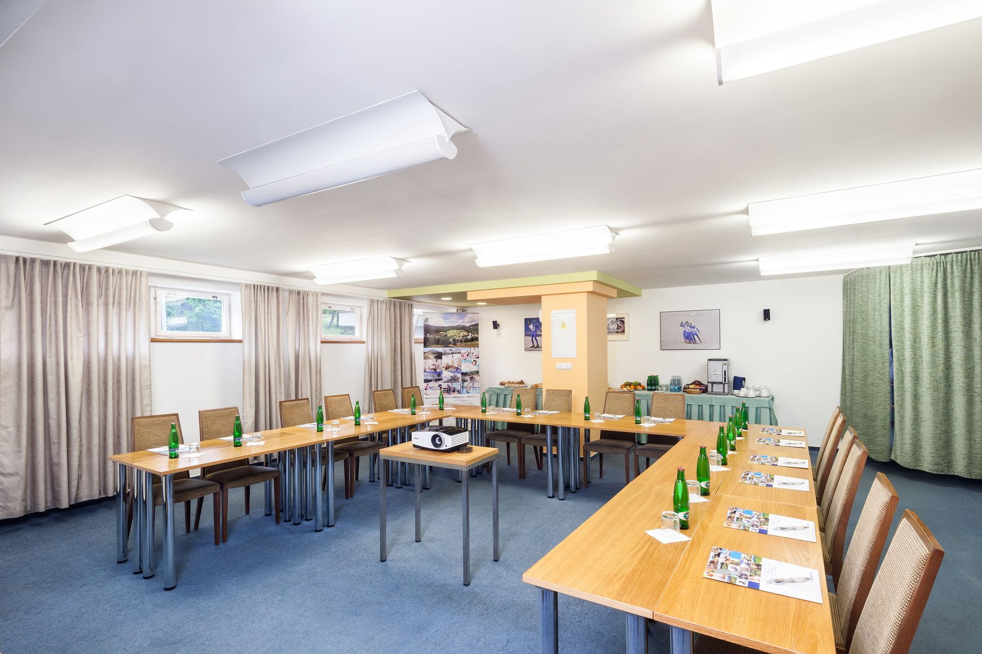 Konferenční místnost se stoly a židlemi připravenými pro jednání