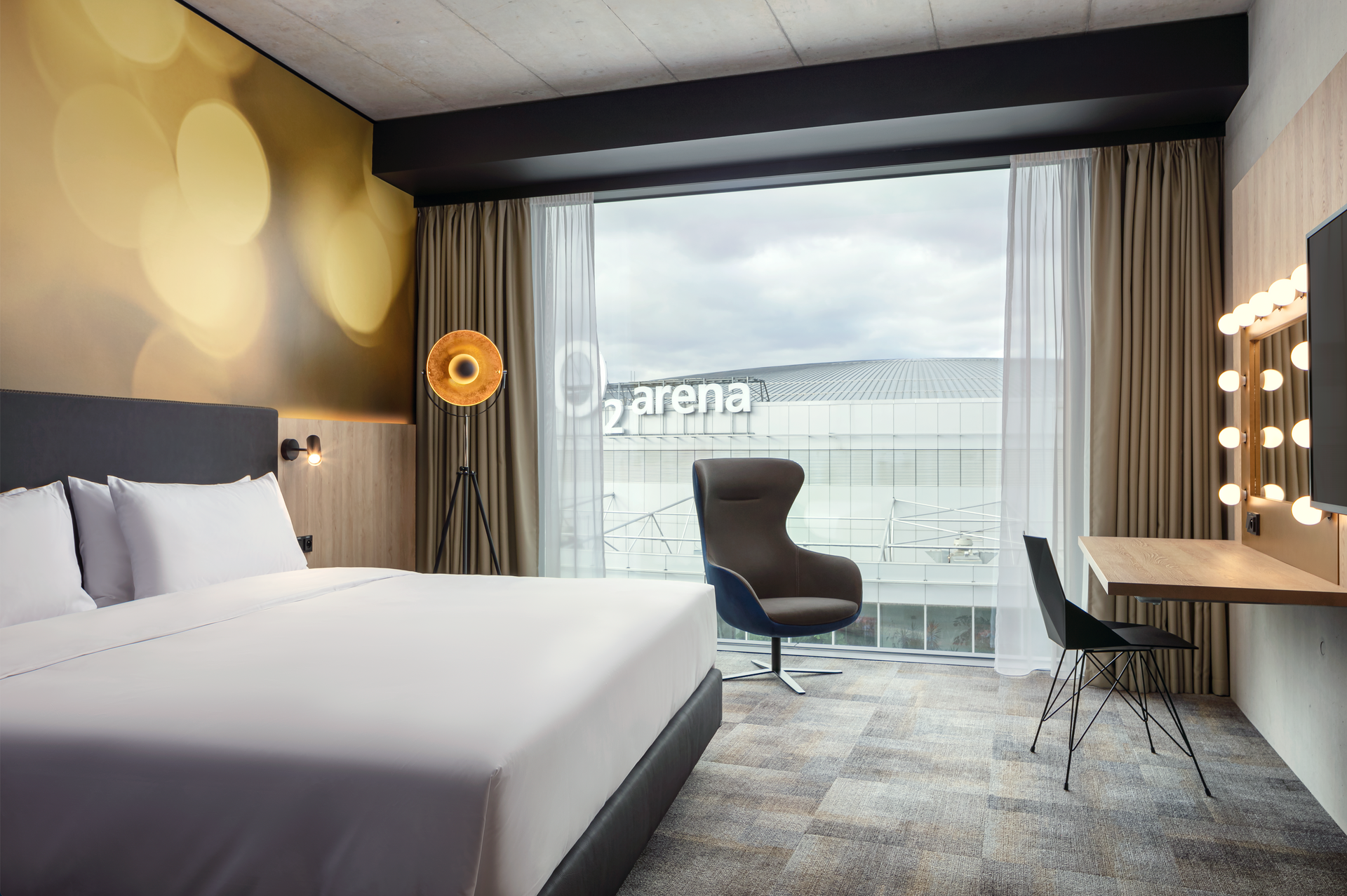 Hotelový pokoj s manželskou postelí , židlí , stolem a zrcadlem.