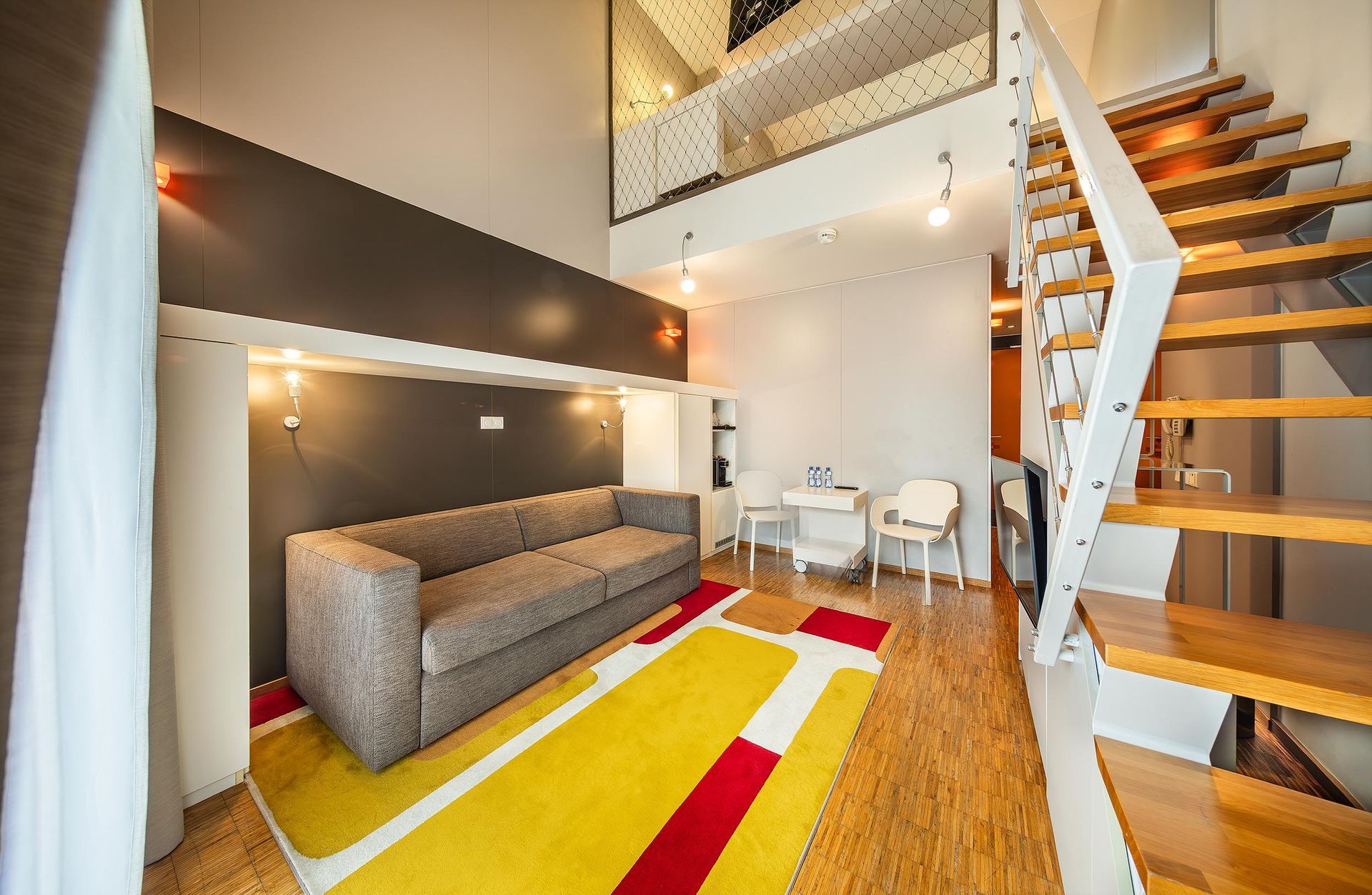 Obývací pokoj s pohovkou a schodiště vedoucí do druhého patra.