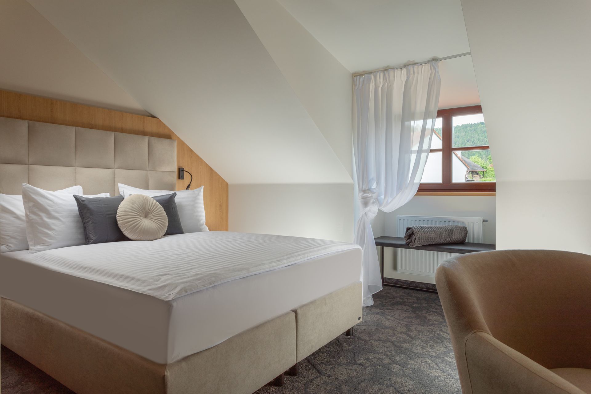 Hotelový pokoj s manželskou postelí velikosti King a židlí.