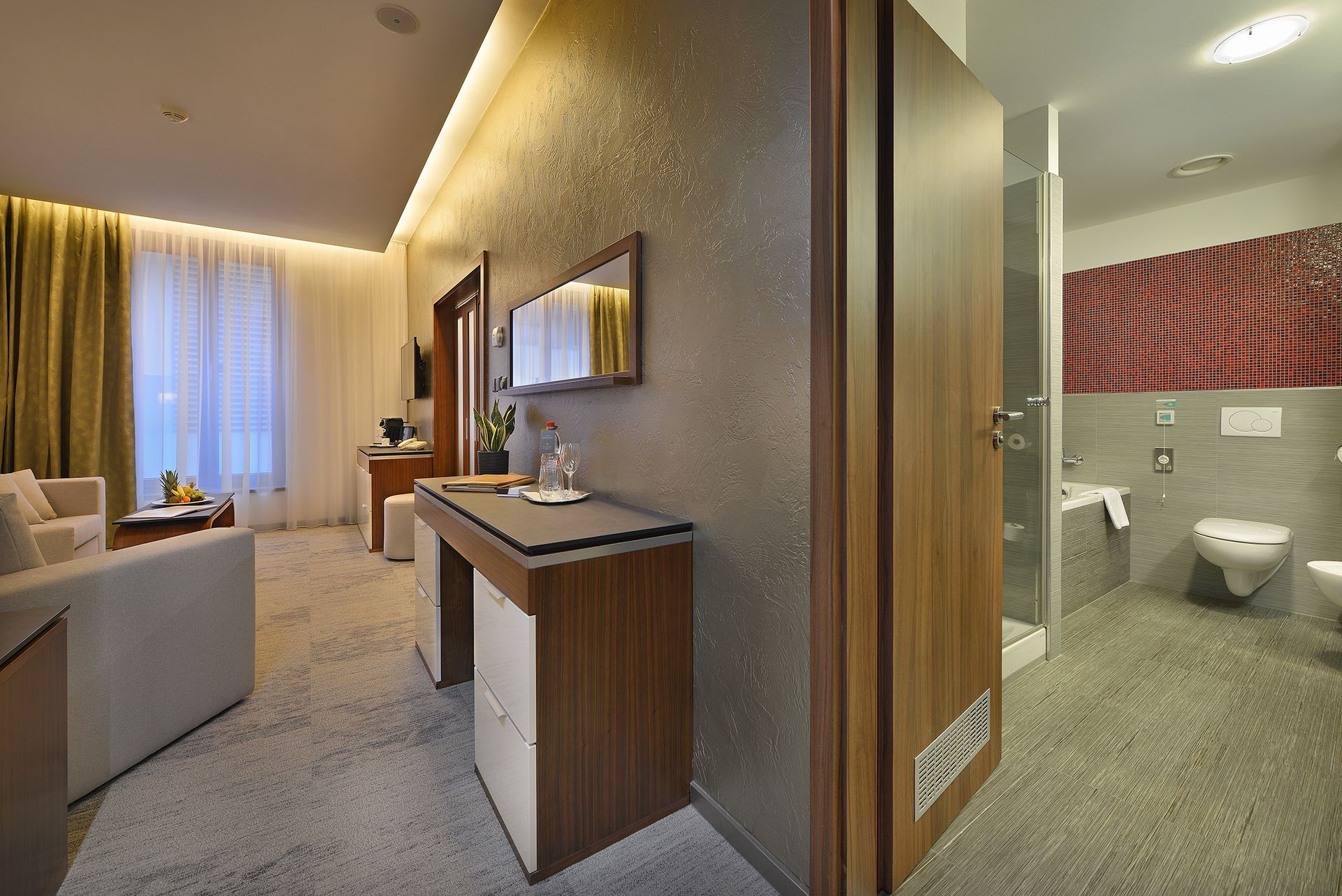 Hotelový pokoj s gaučem , stolem , televizí a postelí.