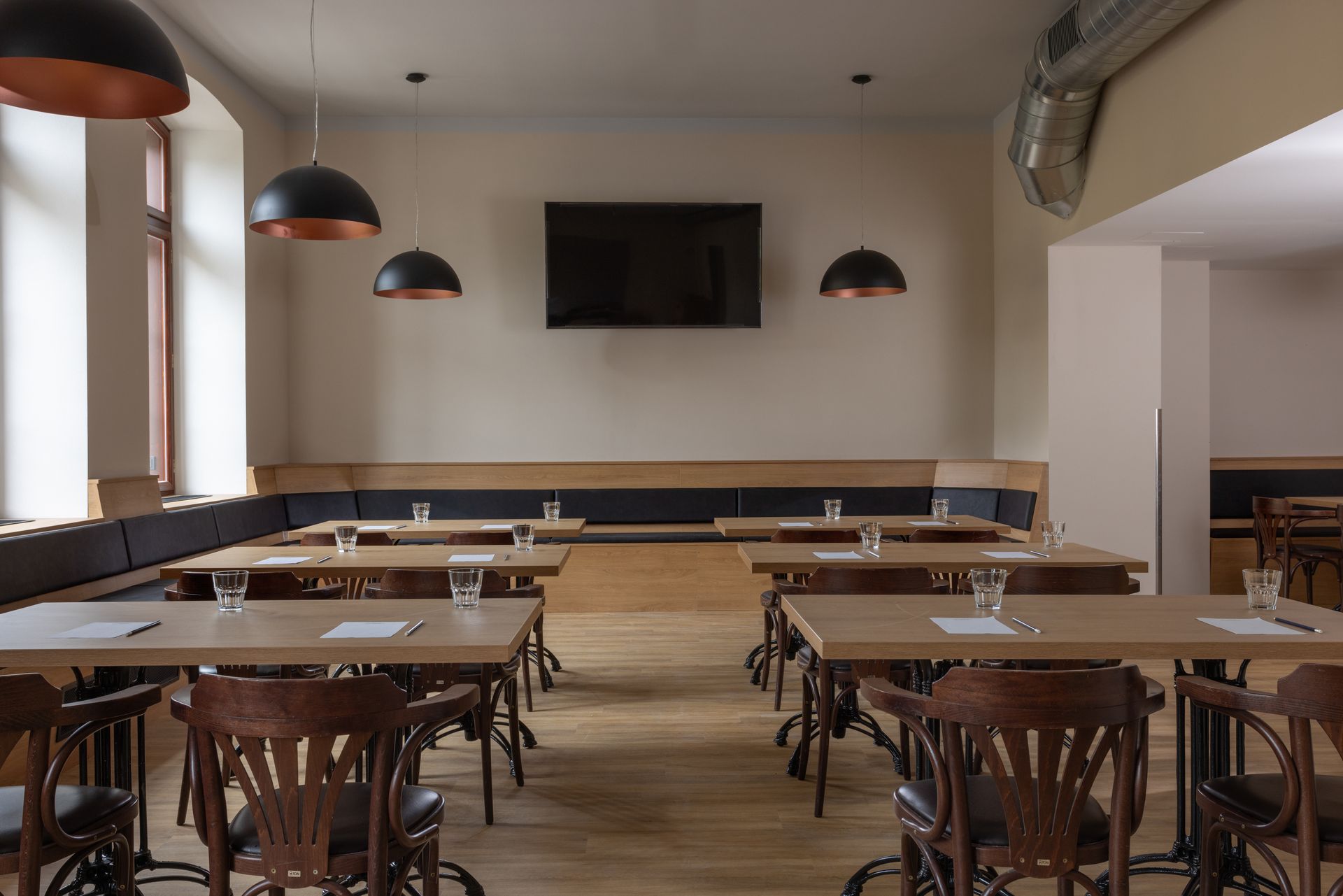 Pokoj se stoly a židlemi a TV s plochou obrazovkou na zdi.