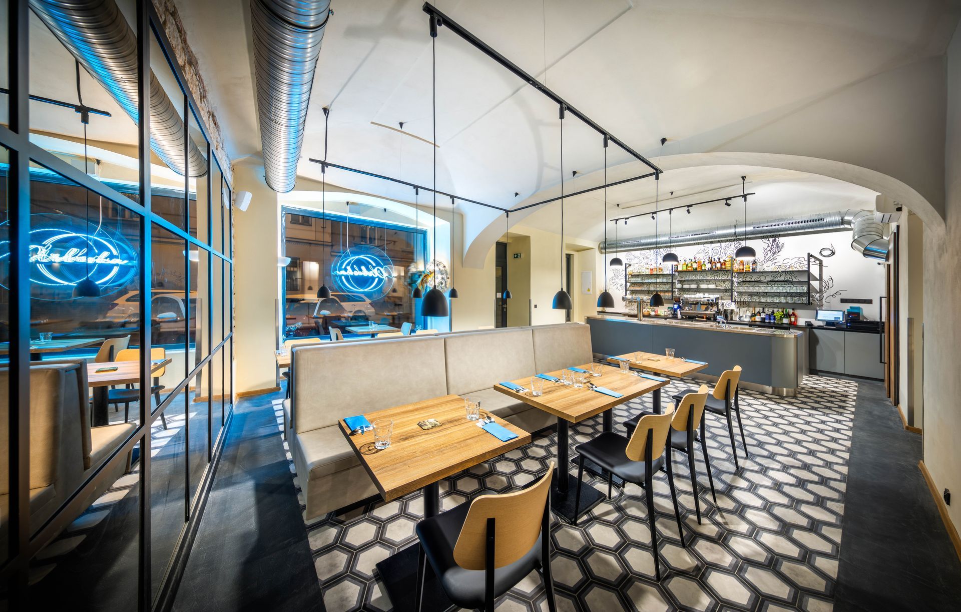 Restaurace se stoly a židlemi a dlouhým gaučem.