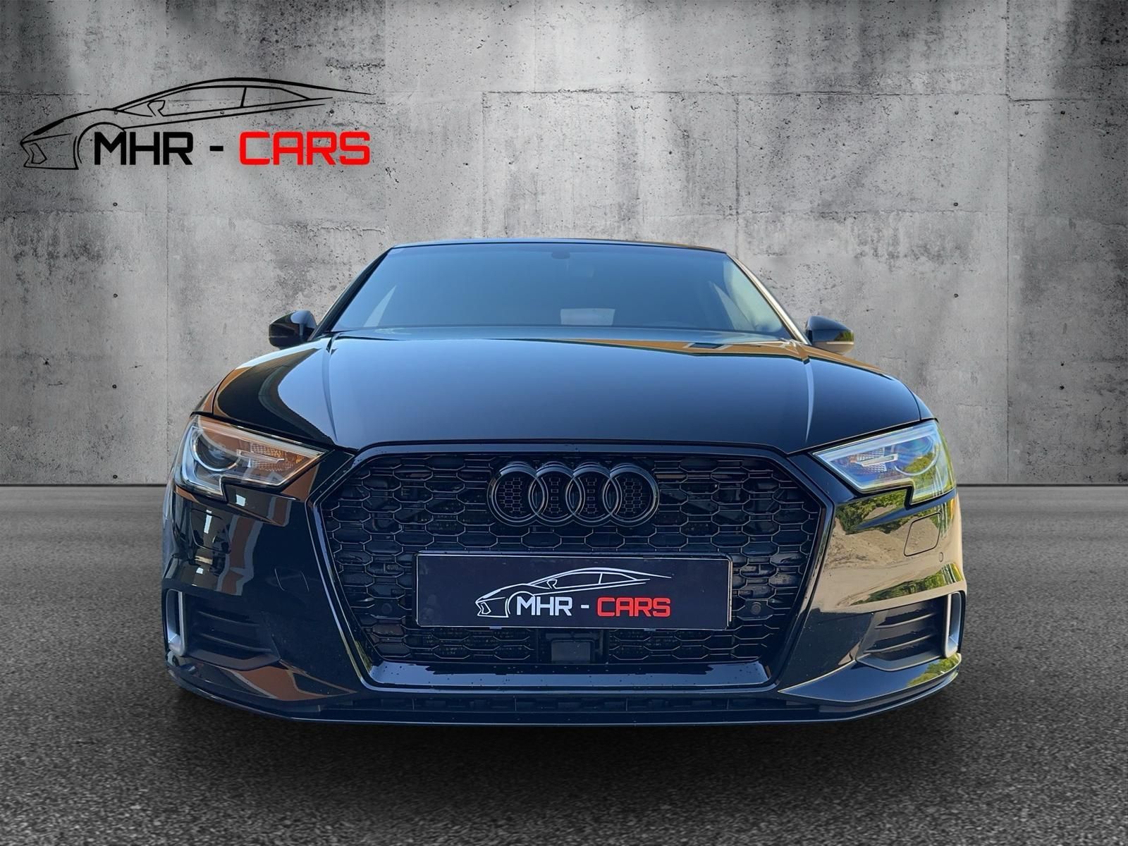 Ein schwarzer Audi A3 parkt vor einer Betonmauer.