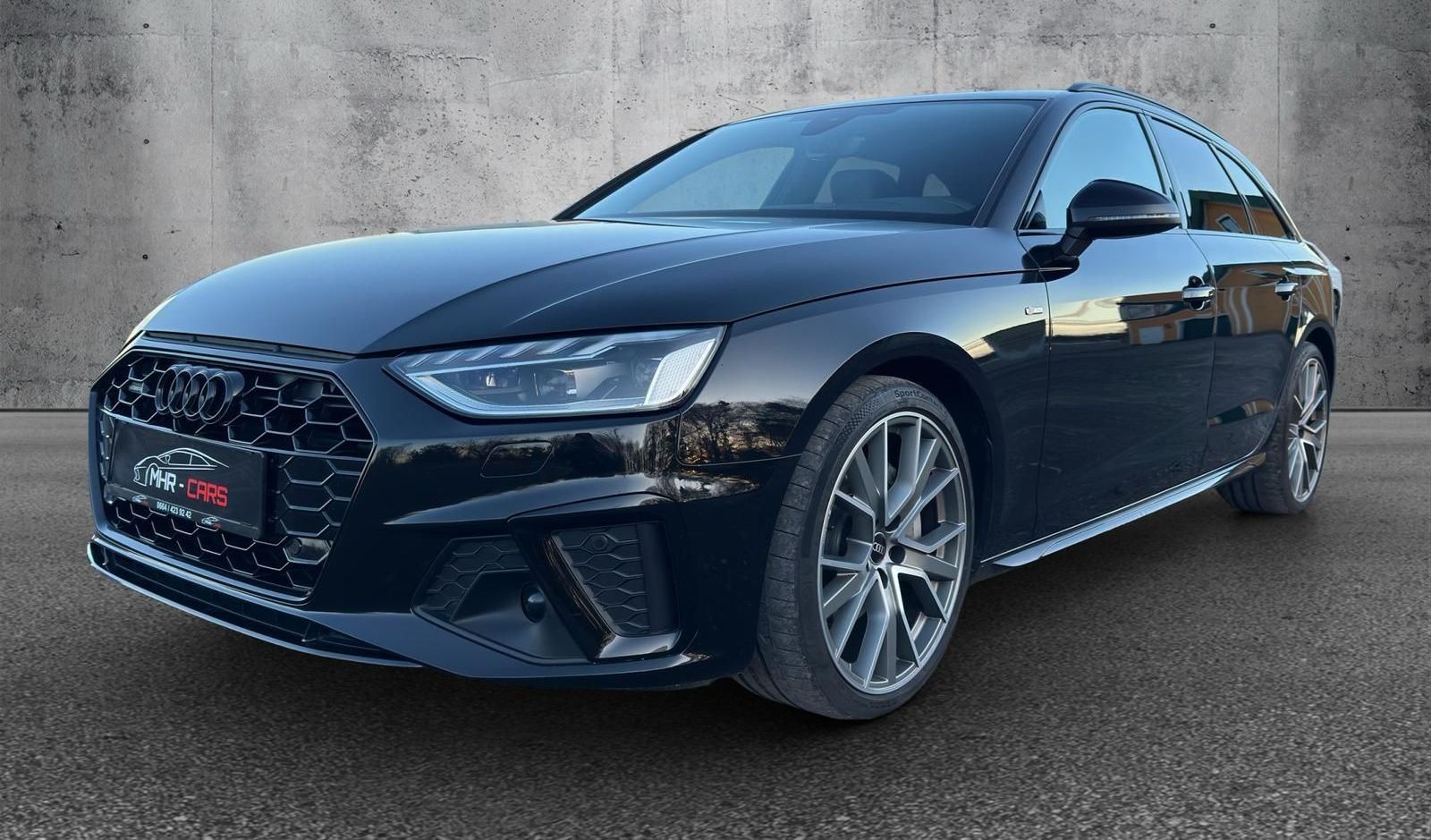 Ein schwarzer Audi A4 parkt vor einer Betonmauer.