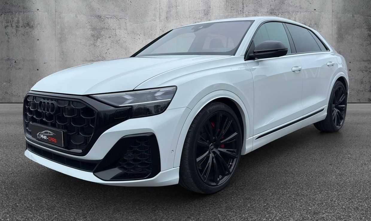Ein weißer Audi Q8 RS parkt vor einer Betonmauer.