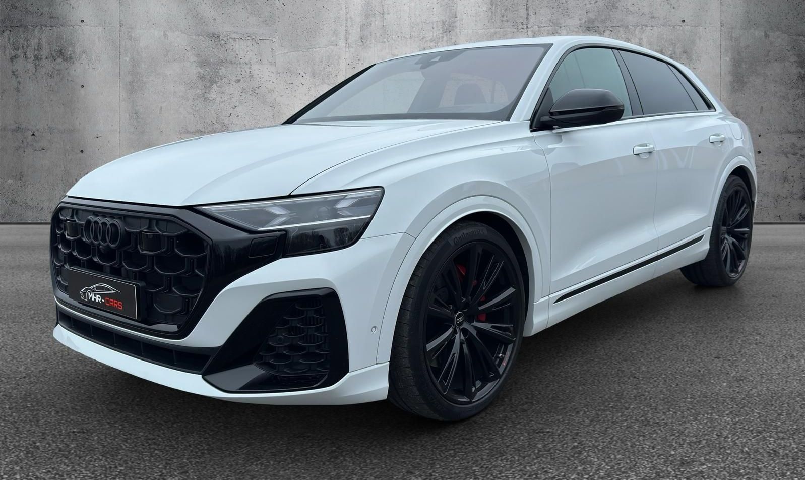 Ein weißer Audi Q8 RS parkt vor einer Betonmauer.