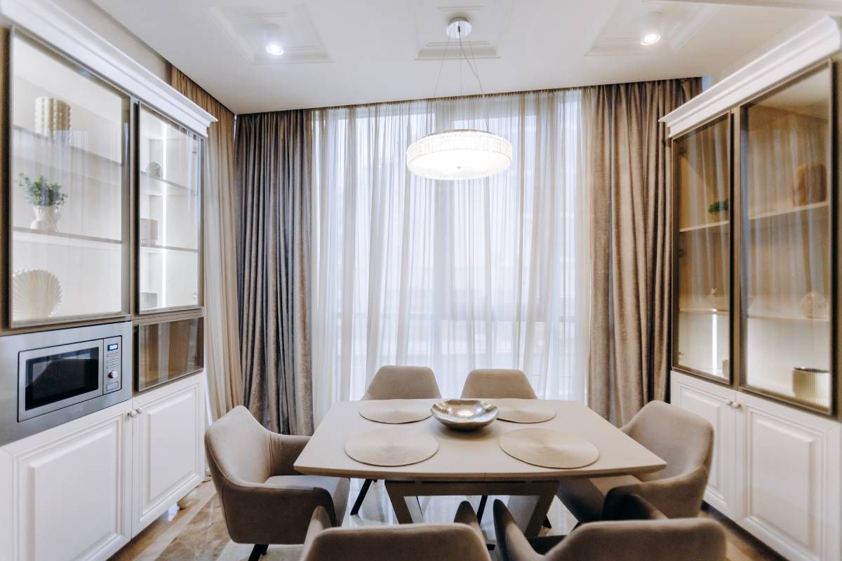 Stunning dining room window treatments with layered drapes, finishing off the cohesive, neutral-colo