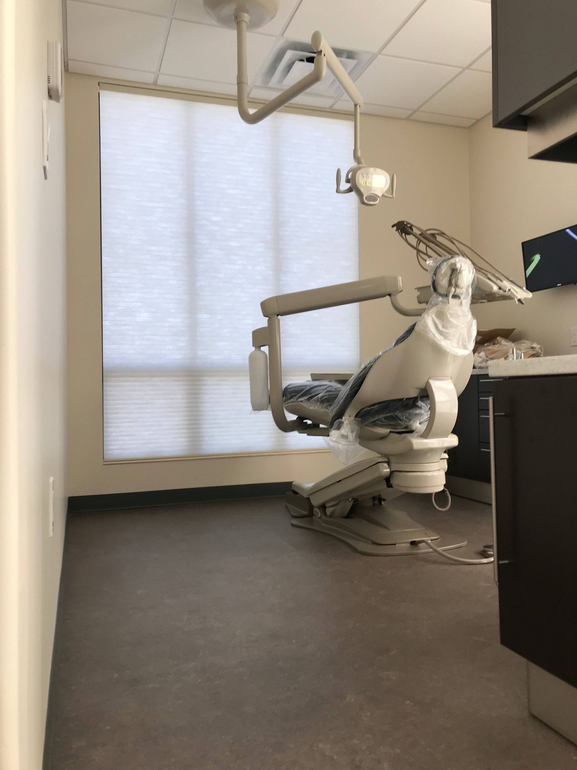 Commercial shades on a tall window in a dentist's office with an exam chair in front of it near Anchorage, AK