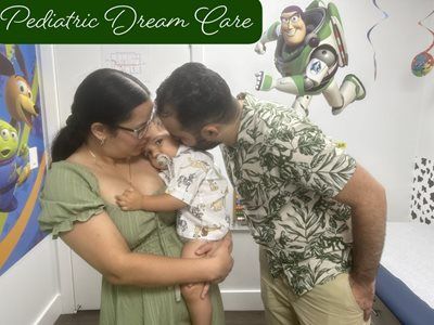 Family embracing: mother holding child, father kissing child's head, decorated room.