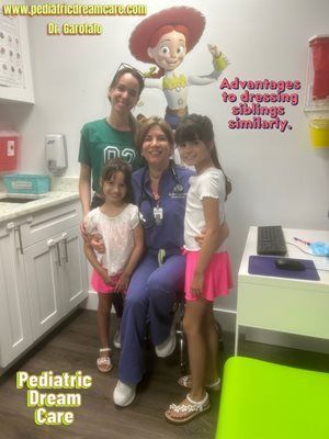 Doctor seated with three girls in a pediatric care office; smiling. Jessie from Toy Story painted on the wall.