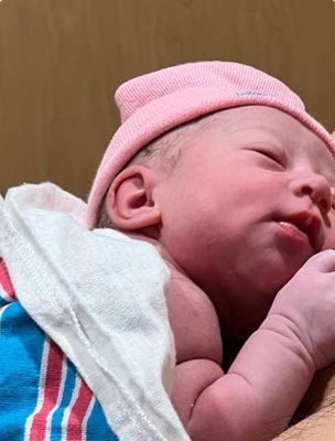Newborn baby wearing a pink hat and wrapped in a hospital blanket. Sleeping peacefully.