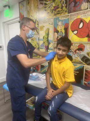 A healthcare worker giving a vaccine to a boy in a clinic. Comic book art decorates the wall.