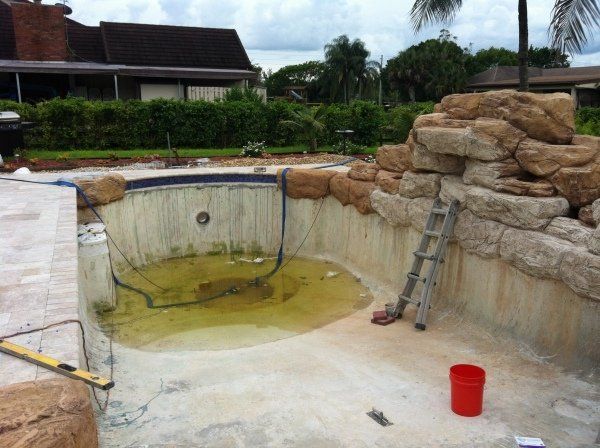 An empty swimming pool with a ladder and a red bucket