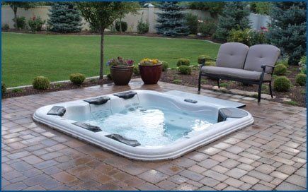 A hot tub is sitting on a patio next to a bench