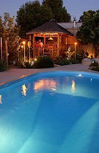 A large swimming pool with a gazebo in the background at night.