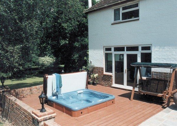 A hot tub on a deck in front of a house