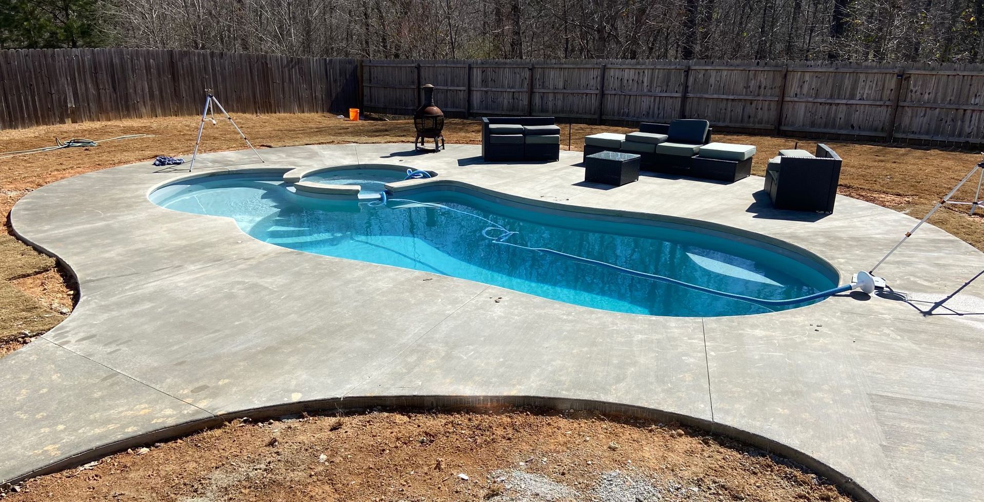 A large swimming pool is sitting on top of a concrete patio in a backyard.
