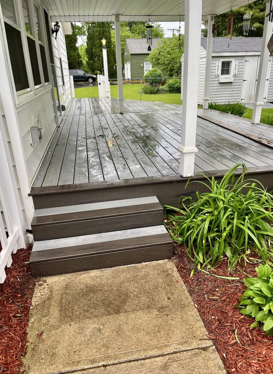 A porch with stairs leading up to it and a walkway leading to it.