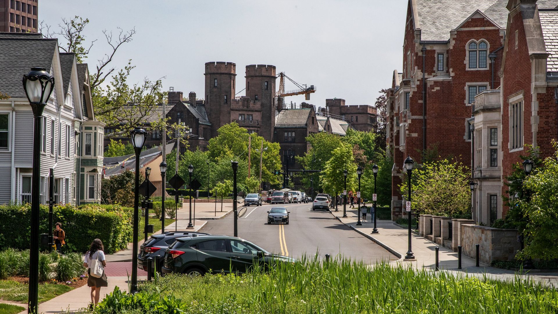 A woman is walking down a sidewalk in a residential neighborhood.