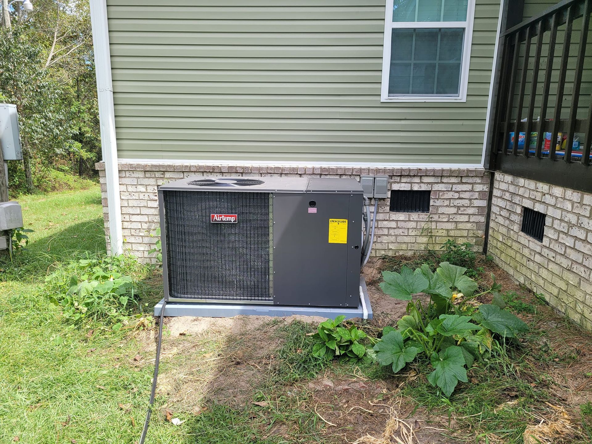 An air conditioner is sitting on the side of a house.