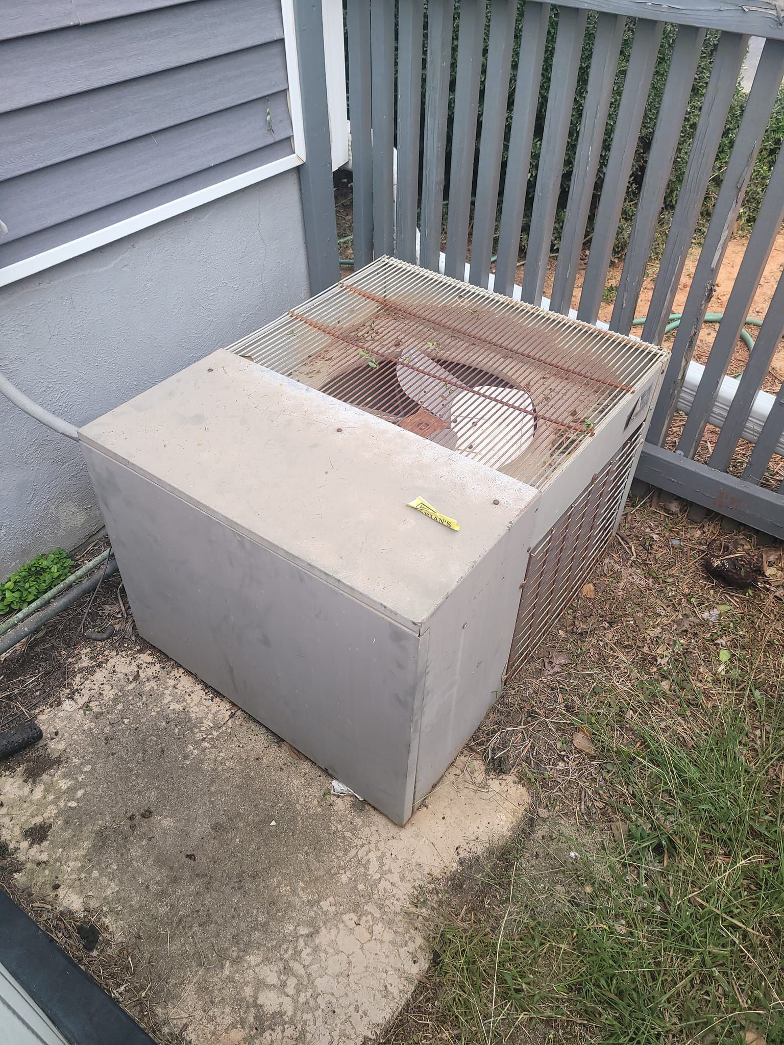 A concrete box is sitting on the ground next to a fence.