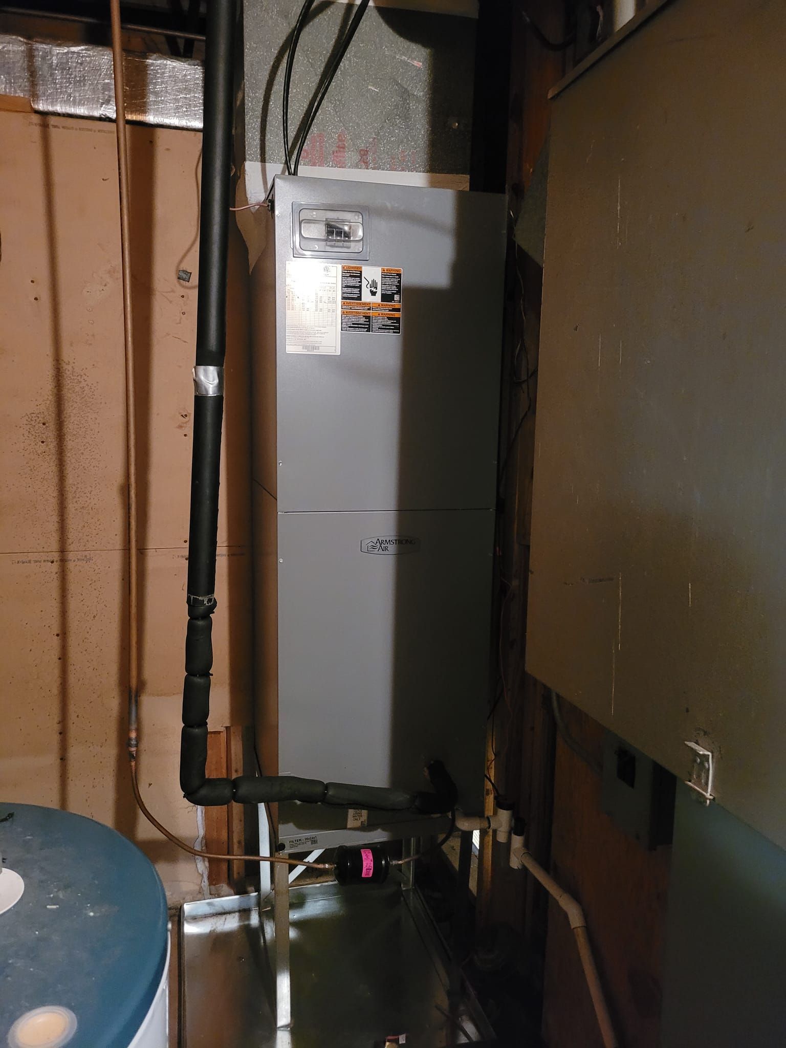 An air conditioner is sitting in a dark room next to a water heater.