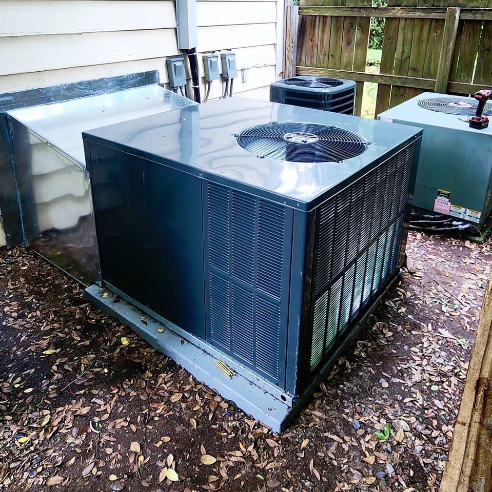 A large air conditioner is sitting on the ground in front of a house.