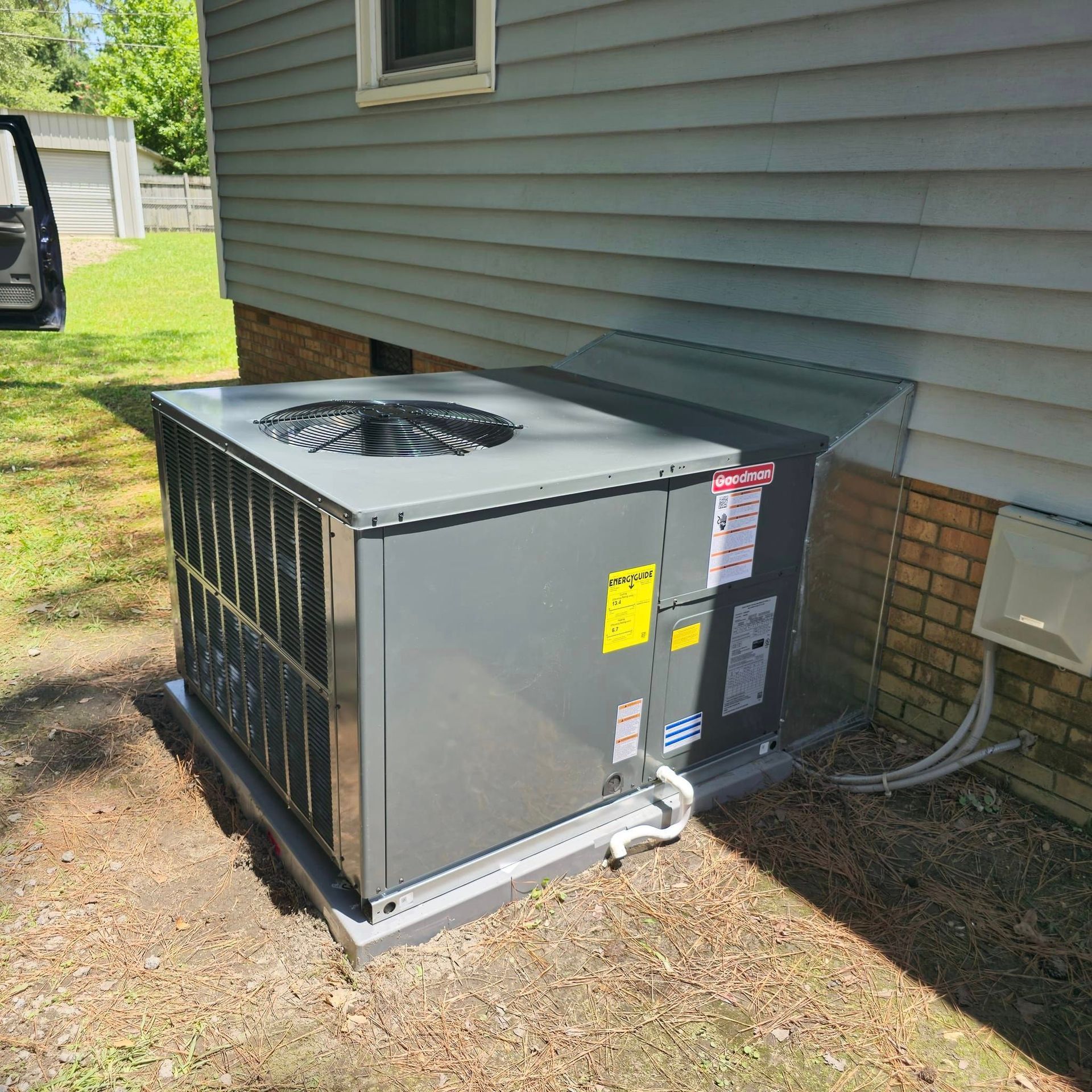 A large air conditioner is sitting on the side of a house.
