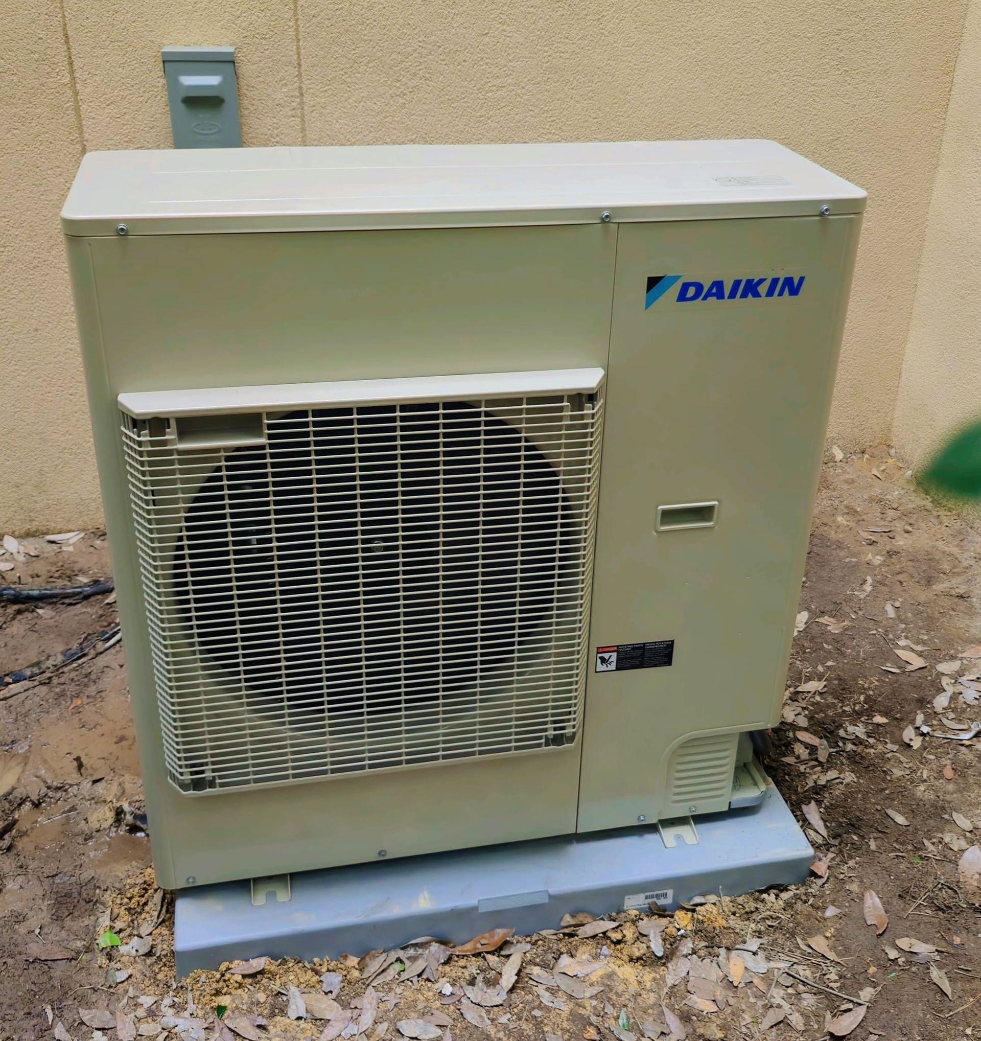 A daikin air conditioner is sitting on the ground outside