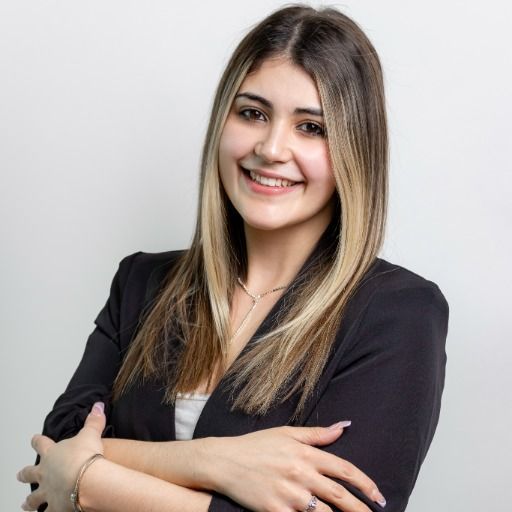 A woman in a black jacket is smiling with her arms crossed.