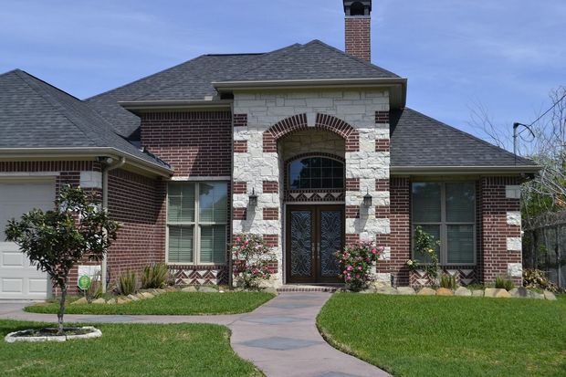 A large brick house with a walkway leading to the front door.