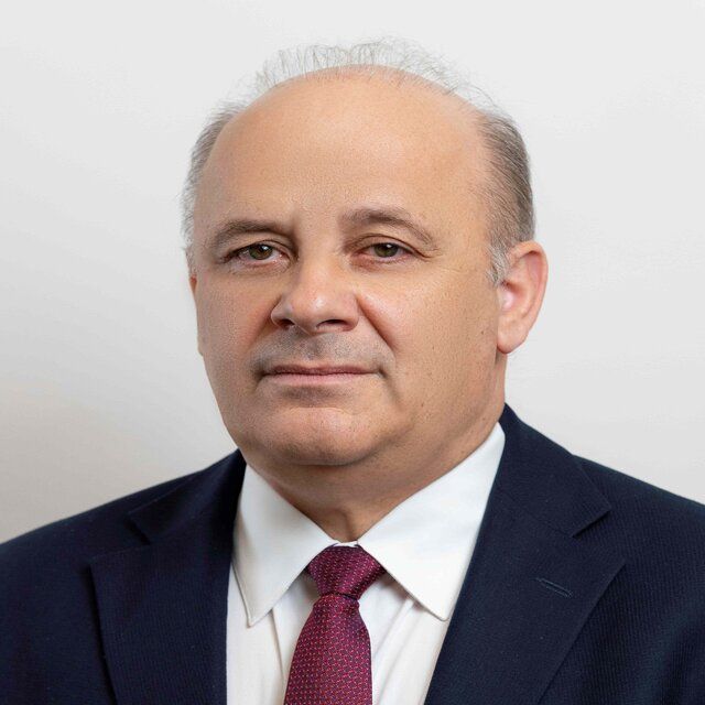 A man in a suit and tie is looking at the camera.