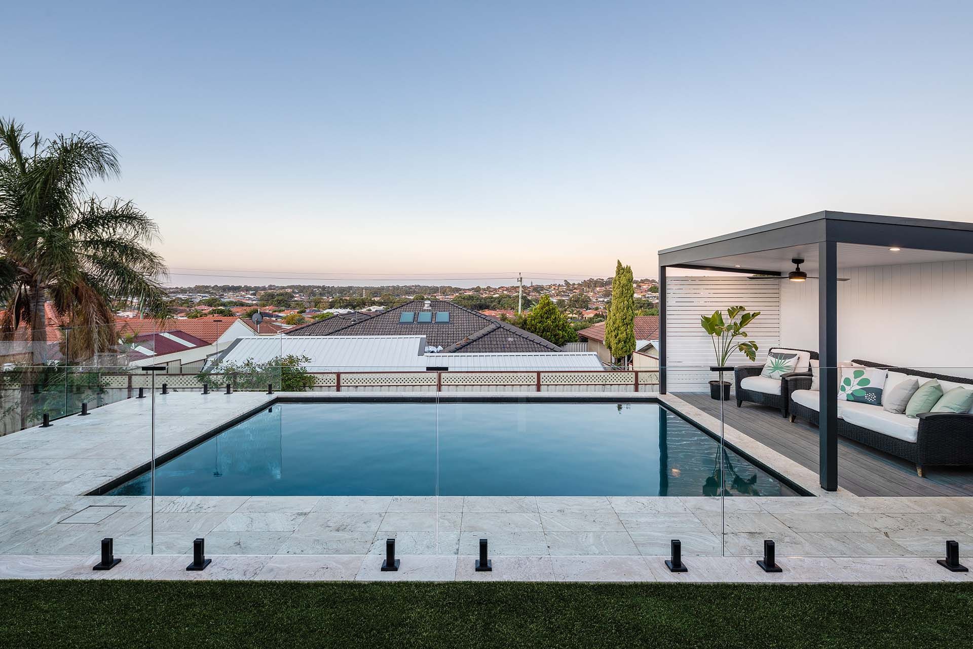 There is a large swimming pool in the backyard of a house.