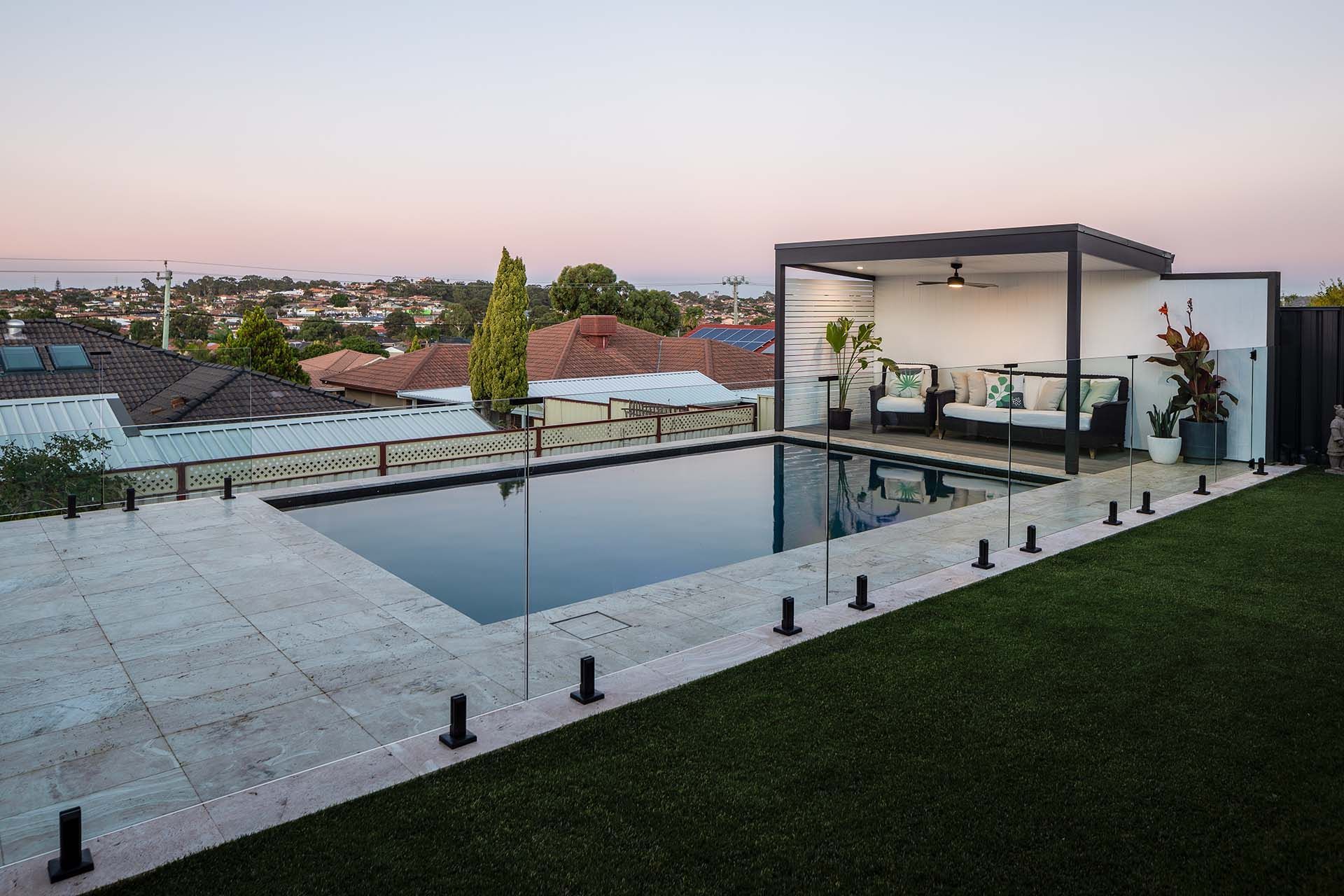 There is a large swimming pool in the backyard of a house.